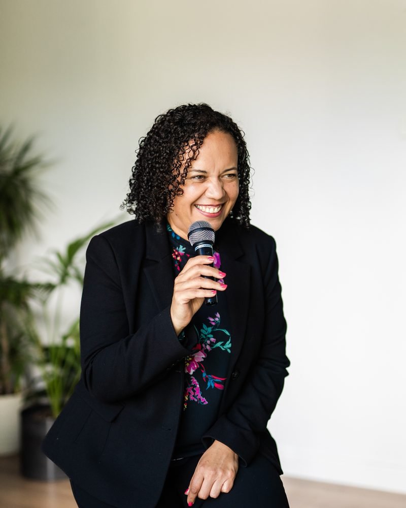 Alicia Noble smiling, holding a microphone