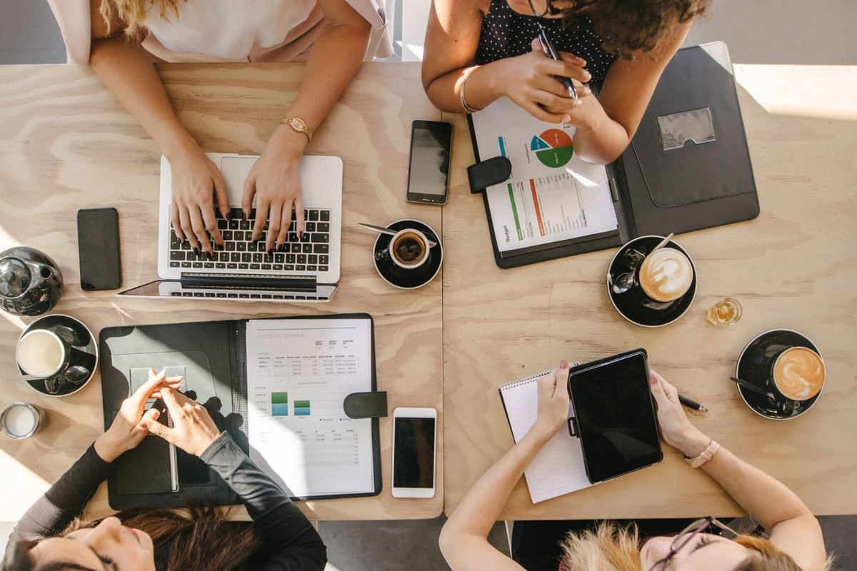 Overhead view of a working table with laptops, notebooks and coffee